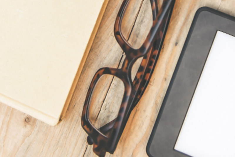 E-Book-Reader mit Brille und Buch
